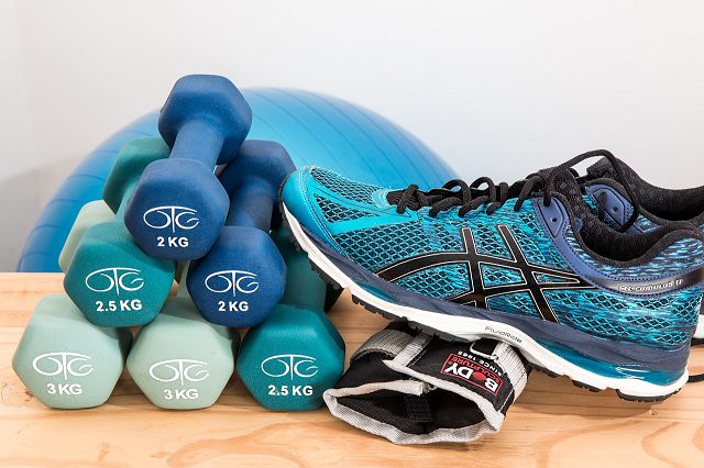 Buty na sale gimnastyczną na zdjęciu przedstawione są buty sportowe oraz hantle w kolorze niebieskim