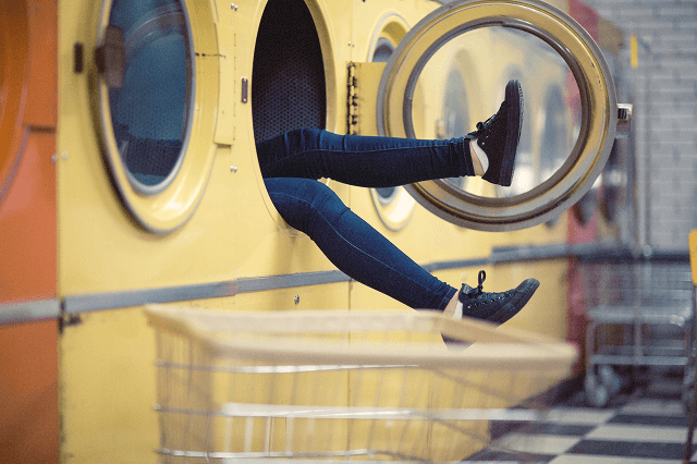 Zdjęcie przedstawia osobę w pralce z nogami poza urządzeniem