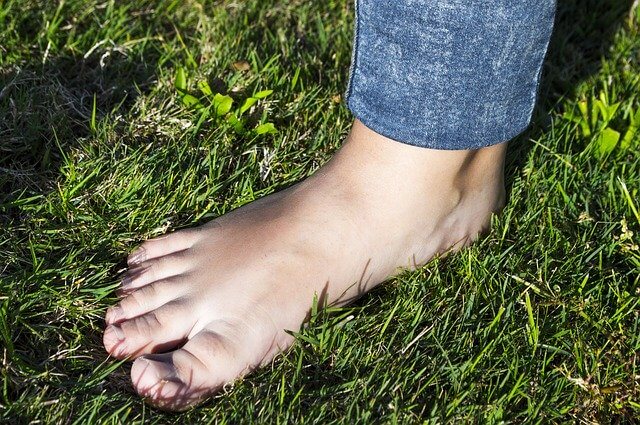 Choroby stóp przedstawiona stopa haluksowa na zielonej trawie